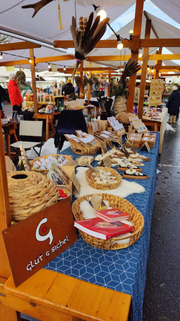 Ein Marktstand mit Kräuterprodukten und Räucherwerk und selbstgemachten Räucherfächern von Glut & Sichel