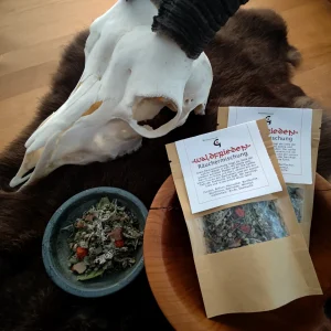 Zwei braune Papiertüten mit der Aufschrift „Waldfrieden – Räuchermischung“ liegen in einer Holzschale auf einem dunklen Fell. Daneben steht eine kleine Schale mit der geöffneten Kräutermischung. Im Hintergrund ist ein weißer Tier­schädel mit Hörnern zu sehen. Die Szene ist in warmem, natürlichem Licht fotografiert und vermittelt eine ruhige, erdige Atmosphäre.
