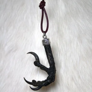 Rabenkralle Anhänger an rotem Lederband vor naturbelassenem Fellhintergrund