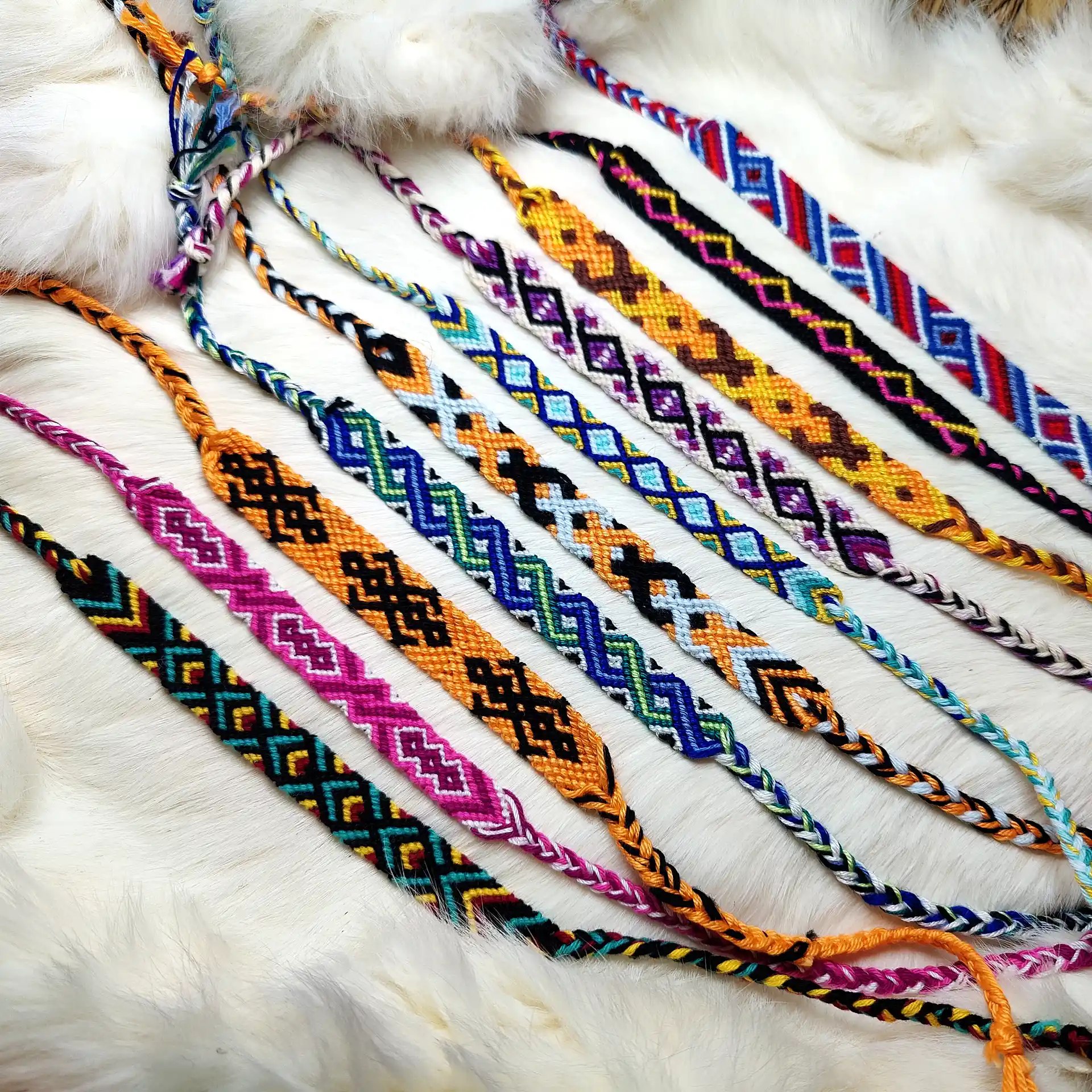 Farbenfrohe, handgeknüpfte Musterbänder mit traditionellen Ornamenten, auf Naturfell ausgelegt.