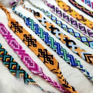 Nahaufnahme handgeknüpfter Freundschafts- und Ritualbänder mit geometrischen Mustern in Blau, Pink, Gelb und Schwarz.